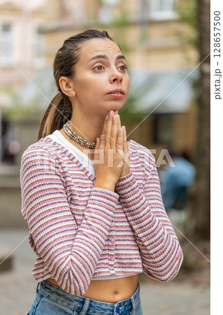 Caucasian young woman praying with closed eyes to God asking for blessing help forgiveness outdoors 128657500