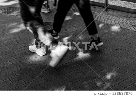 Urban Steps - People Walking on Sunlit Pavement Urban Steps - People Walking on Sunlit Pavement 128657876
