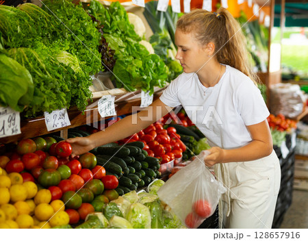 Fifteen-year-old girl shopper chooses fresh tomatoes Fifteen-year-old girl shopper chooses fresh tomatoes 128657916