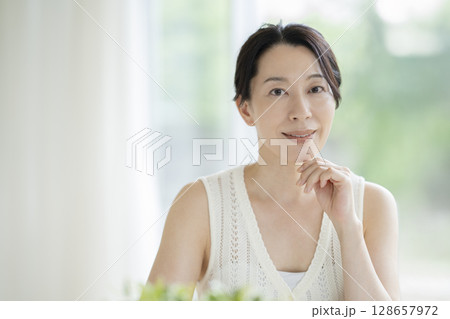 カメラ目線で微笑むアラフィフの女性　ビューティーイメージ　ポートレート 128657972