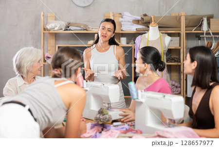 Female sewing teacher explaining garment construction to group of beginners 128657977