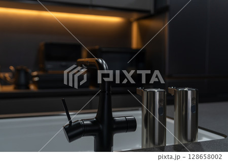 間接照明と黒を基調としたスタイリッシュなシステムキッチン、食器洗い機とシンク、ihクッキングヒーター 128658002