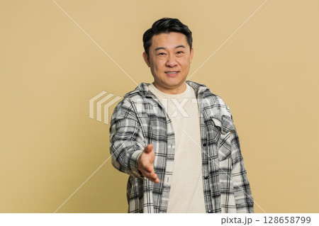 Asian mature man outstretching hand to camera, offering handshake, greeting, invitation, welcoming 128658799