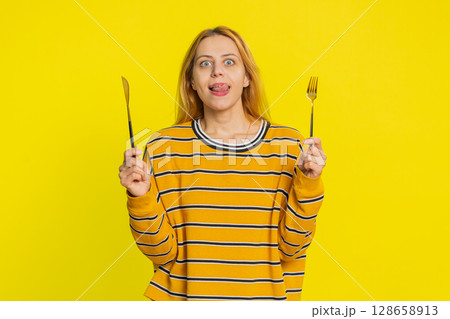Hungry woman waiting for serving dinner meal dishes with restlessness holding cutlery fork knife Hungry woman waiting for serving dinner meal dishes with restlessness holding cutlery fork knife 128658913