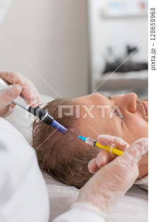Trichologist doing man improve hair growth procedure, dermapen microneedling, vitamin injections 128658968