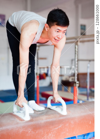 Male athlete doing complicated exciting trick on pommel horse in professional gym Male athlete doing complicated exciting trick on pommel horse in professional gym 128661000