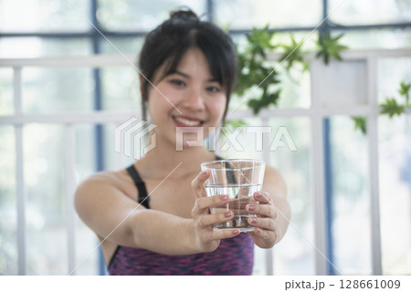 Woman drinking water hands holding cold mineral water cool drinking. Asian women smile laugh look away health care home fitness lifestyle. Cheerful Beautiful female drink glass of water smile face 128661009