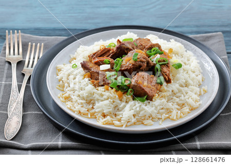 beef slow cooked with gravy served over rice 128661476