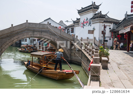 Chinese waterman paddle boat to bridge to city god temple, Zhujiajiao 128661634