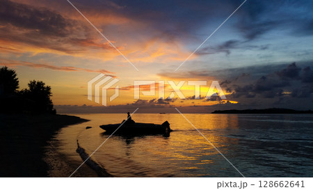 beautiful dramatic landscape of sunset on sea beach with silhouette of boat 128662641
