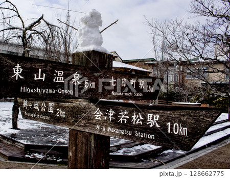 木製の行先案内の上に可愛い雪だるまが乗っている風景 128662775
