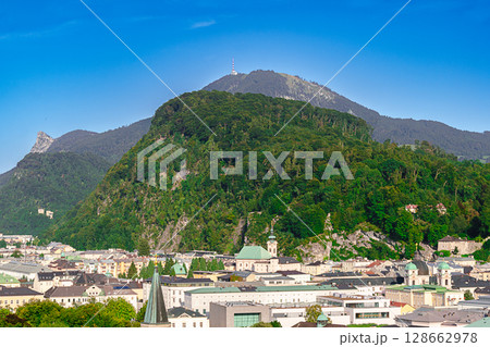 View over city of Salzburg in Austria, to Linzergasse with St. Sebastian Church at the foot of scenic hill Kapuzinerberg. In the back local mountain Gaisberg, and to the left the rocky peak Nockstein. 128662978