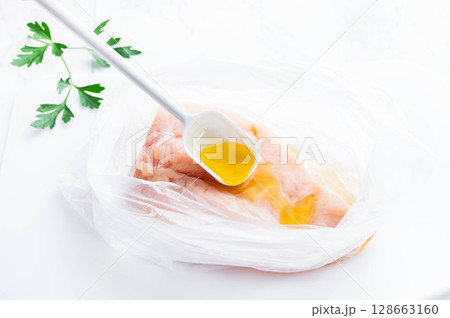 鶏むね肉にオリーブオイルを加える 鶏むね肉にオリーブオイルを加える 128663160