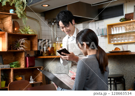 飲食店で接客するアジア人の男性の店員 飲食店で接客するアジア人の男性の店員 128663534