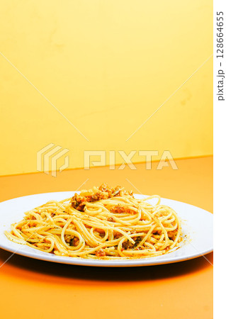 A classic plate of spaghetti with a rich, savory meat sauce, served on a white dish against an orange background. A classic plate of spaghetti with a rich, savory meat sauce, served on a white dish against an orange background. 128664655