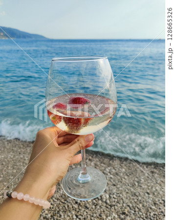 a glass with a drink on the beach near the sea 128665326