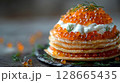 Elements of the Caviar Blini Tower levitate elegantly, showcasing layers of delicate blinis, rich cremer fraiche, and generous caviar, topped with a sprig of dill 128665435