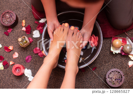 a masseuse in a cosmetology salon makes a Thai massage on the legs of a young girl 128665827