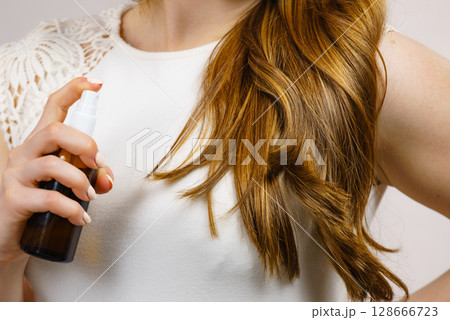 Woman applying hair cosmetic 128666723