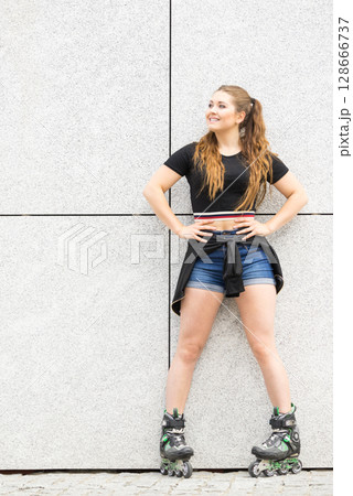 Young woman riding roller skates 128666737