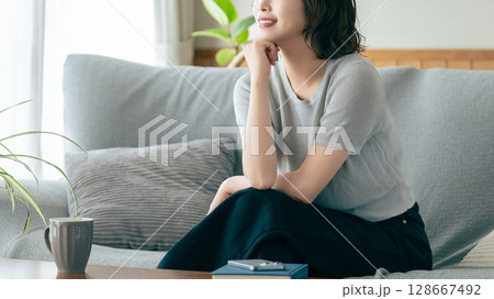 リビングのソファに座る笑顔の女性 リビングのソファに座る笑顔の女性 128667492