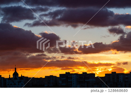 beautiful colored sky and thick clouds at sunset on the horizon city silhouette 128668680