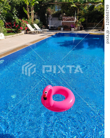 a toy pink flamingo is swimming in beautiful large swimming pool near the house a toy pink flamingo is swimming in beautiful large swimming pool near the house 128668749