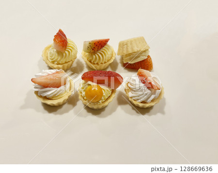 Delicious mini fruit tarts arranged next to each other, with one flipped over. 128669636