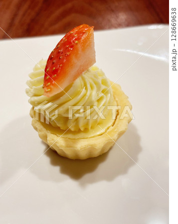 Closeup of a single mini strawberry tart, served on a white porcelain plate. Closeup of a single mini strawberry tart, served on a white porcelain plate. 128669638
