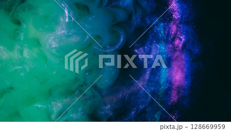 Swirling fluid. Paint background. Defocused yellow purple neon color smoke glitter rainbow splash liquid spreading on dark black abstraction. 128669959