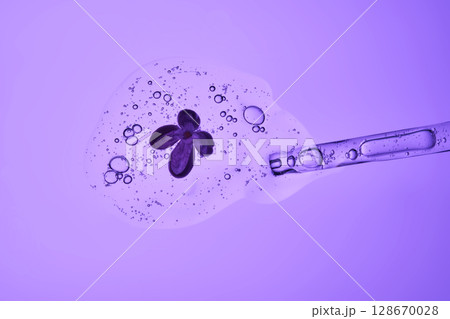 The beautiful texture of the serum with bubbles and a lilac flower pours out of the pipette. The beautiful texture of the serum with bubbles and a lilac flower pours out of the pipette. 128670028
