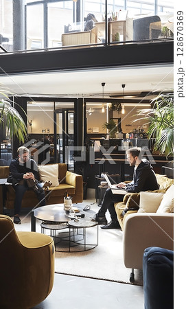 A man and a woman are sitting on a couch in a room with a lot of plants A man and a woman are sitting on a couch in a room with a lot of plants 128670369