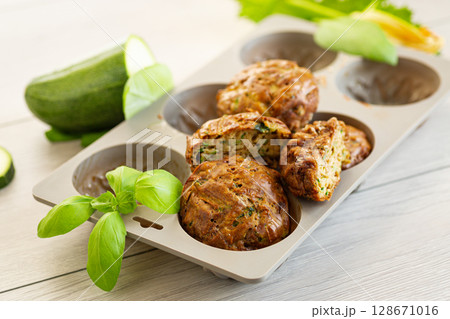 Vegetarian zucchini muffins in a bright presentation on a light wooden table Vegetarian zucchini muffins in a bright presentation on a light wooden table 128671016