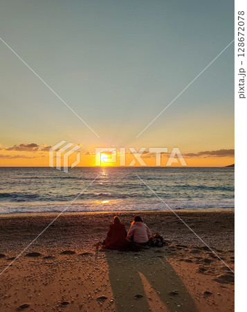 silhouette of people relaxing on the beach at sunset 128672078