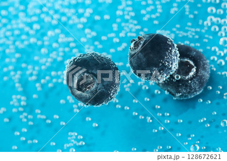 Fresh blueberries float in sparkling water, surrounded by bubbles, creating an inviting and colorful look Fresh blueberries float in sparkling water, surrounded by bubbles, creating an inviting and colorful look 128672621