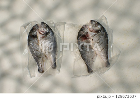 Raw dorado fish are placed on transparent packaging, showcasing their silver skin and fresh appearance. Raw dorado fish are placed on transparent packaging, showcasing their silver skin and fresh appearance. 128672637
