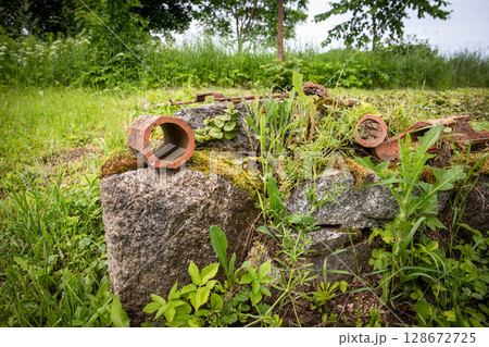 Overgrown Rubble with Moss, Stones and Rusted Clay Pipes in a Rural Abandoned Field 128672725