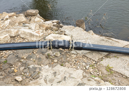 Large diameter irrigation water pipe going into a river 128672808