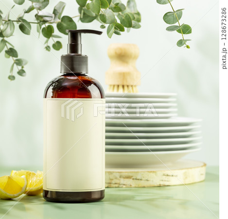 Mockup of natural dish detergent. Eco friendly cleaning dishes. Sustainable still life with bottle with dish detergent with clean plates on blue background with lemon slices and sprig of eucalyptus 128673286