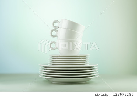 Clean, empty white dishes and cups on blue gradient background. Eco friendly washing dishes and cleaning. Dishes, porcelain background. Front view Clean, empty white dishes and cups on blue gradient background. Eco friendly washing dishes and cleaning. Dishes, porcelain background. Front view 128673289
