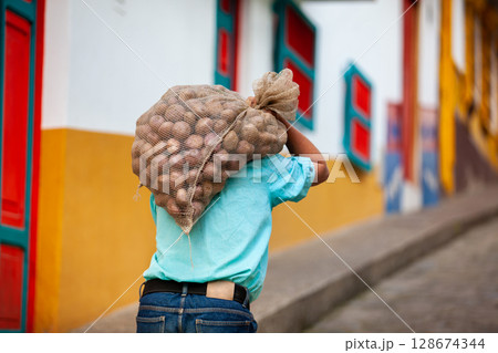 Peasant man carrying a sack of potatoes at the small town of Concepcion, Antioquia, Colombia. 128674344