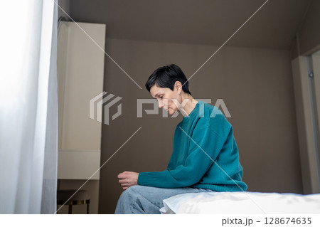 Agoraphobia, social fear anxiety and isolation. Depressed drained woman sit on bed arms crossed 128674635