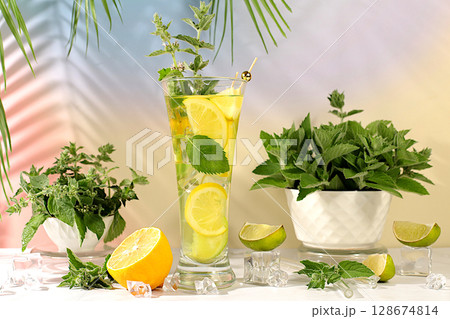 Mint alcoholic or non-alcoholic cocktail with lemon, lime, mint and ice. Modern still life with summer drinks for detox diet. Minimalistic concept for bar, advertising banner for cafe Mint alcoholic or non-alcoholic cocktail with lemon, lime, mint and ice. Modern still life with summer drinks for detox diet. Minimalistic concept for bar, advertising banner for cafe 128674814
