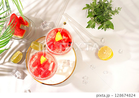 Ice punch with watermelon slices, lemon, mint, ice with tequila, vodka or soda water on elegant background, minimalist concept for bar, soft drink for weight loss and detox diet, advertising banner 128674824