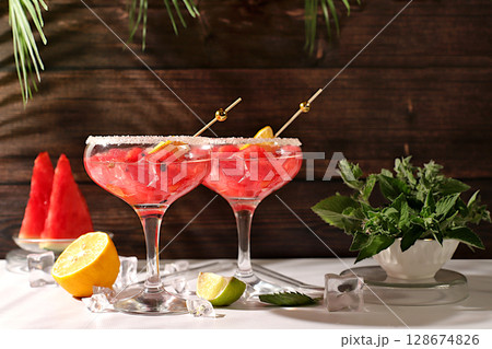 Ice punch with watermelon slices, lemon, mint, ice with tequila, vodka or soda water on elegant background, minimalist concept for bar, soft drink for weight loss and detox diet, advertising banner 128674826