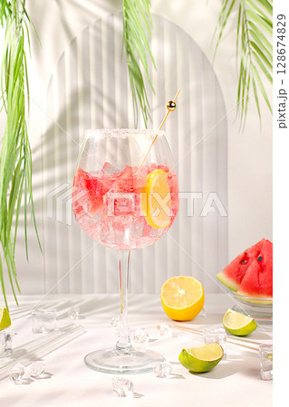 Modern still life with alcoholic cocktail of watermelon, lemon, ice, tequila, vodka and mint on elegant background, minimalist concept for bar, recipe of spanish sangria, advertising banner for cafe 128674829