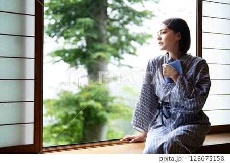 浴衣姿で旅館の窓際に座る若い女性 128675158