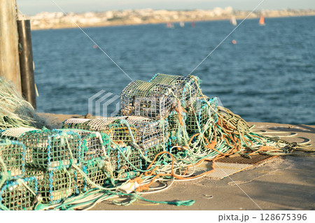 Crab Traps Arranged on a Dock Near the Water in a Crab Traps Arranged on a Dock Near the Water in a 128675396