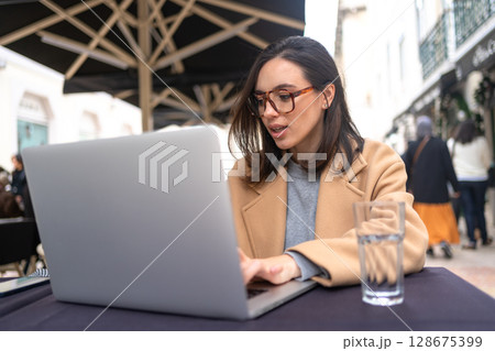Woman working on remote from outdoor cafe 128675399