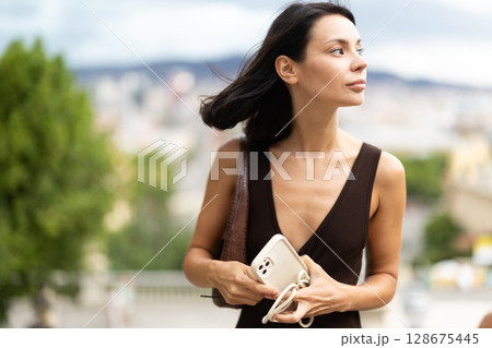 Woman walks through historical center of Barcelona with phone 128675445
